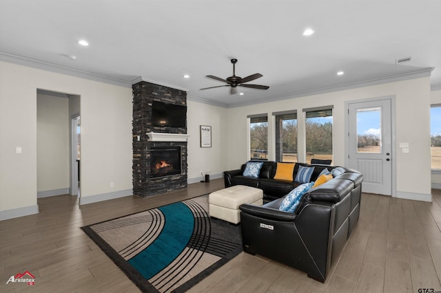 living room featuring hardwood / wood-style flooring, crown molding, ceiling fan, and a fireplace