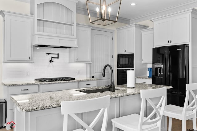 kitchen featuring a kitchen bar, a kitchen island with sink, sink, and black appliances