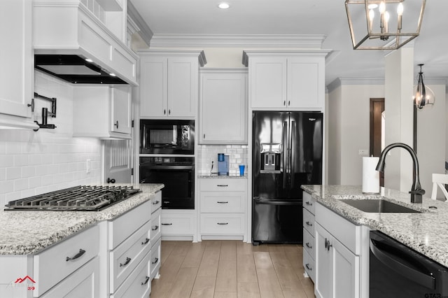 kitchen with sink, custom exhaust hood, black appliances, hanging light fixtures, and white cabinets