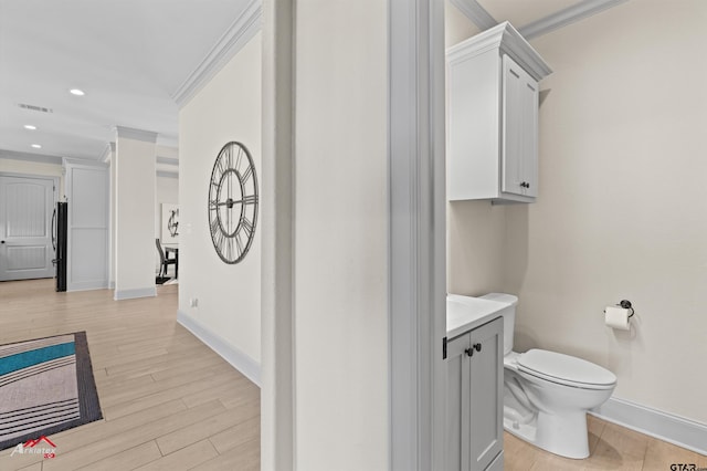 bathroom featuring hardwood / wood-style flooring, ornamental molding, toilet, and vanity