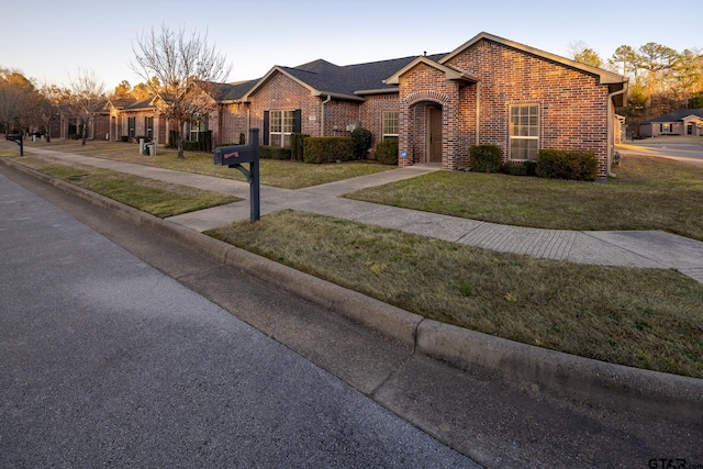 single story home with roof with shingles, brick siding, and a front lawn