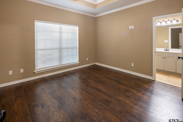 spare room featuring baseboards, ornamental molding, a sink, and wood finished floors