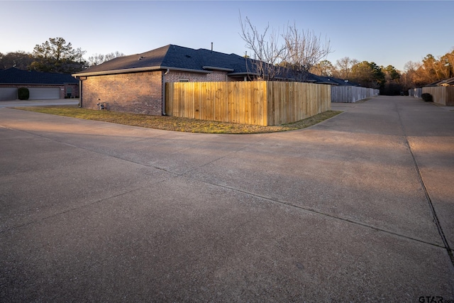 view of side of home featuring brick siding and fence