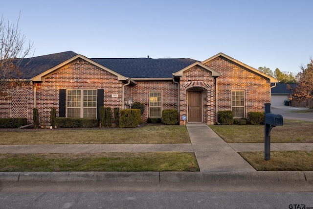 ranch-style house with brick siding, a shingled roof, and a front yard