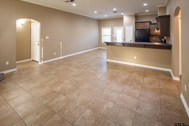 kitchen featuring arched walkways, ornamental molding, freestanding refrigerator, and baseboards