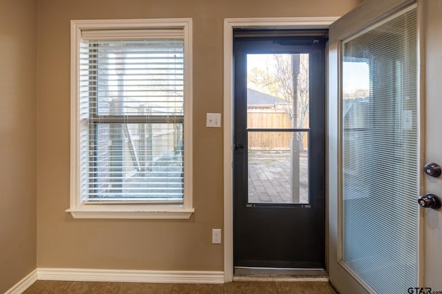 doorway with a healthy amount of sunlight, baseboards, and tile patterned floors