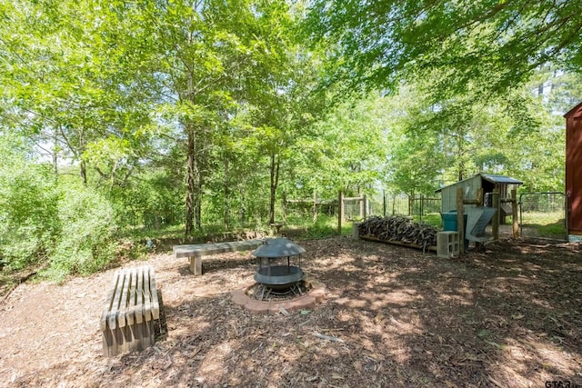 view of yard featuring fence, a fire pit, and an outbuilding