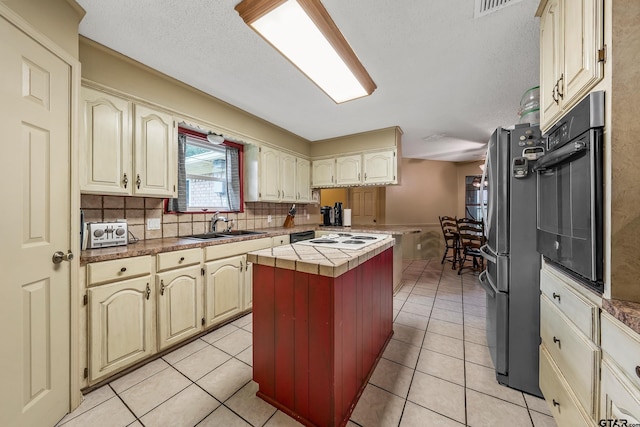 kitchen featuring tasteful backsplash, black oven, stainless steel fridge, and light tile patterned floors