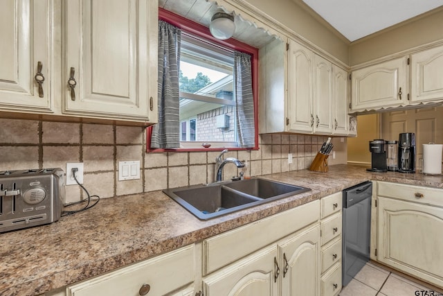 kitchen with decorative backsplash, stainless steel dishwasher, sink, light tile patterned floors, and cream cabinetry