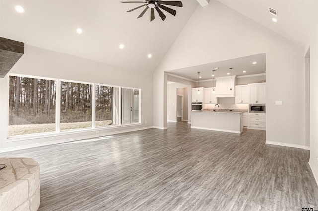 unfurnished living room with sink, beamed ceiling, ceiling fan, dark hardwood / wood-style floors, and high vaulted ceiling