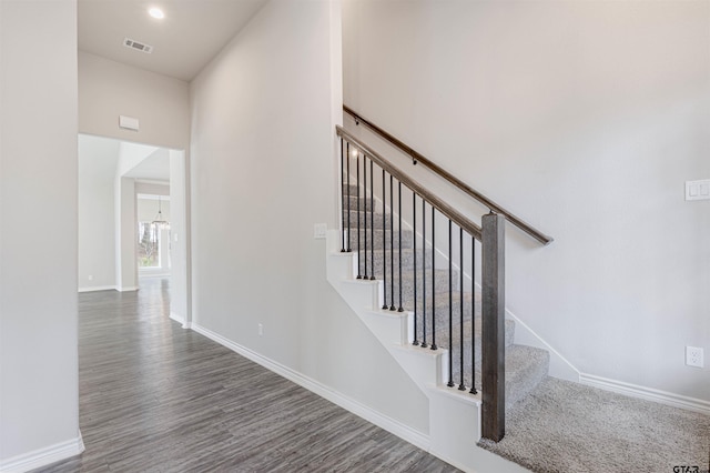 stairway featuring hardwood / wood-style flooring and a chandelier