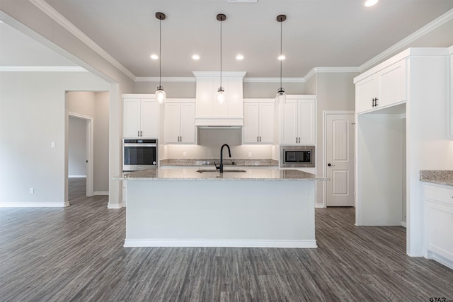 kitchen with appliances with stainless steel finishes, white cabinets, a kitchen island with sink, and light stone countertops