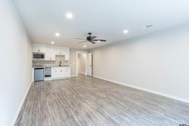 unfurnished living room with sink, light wood-type flooring, and ceiling fan