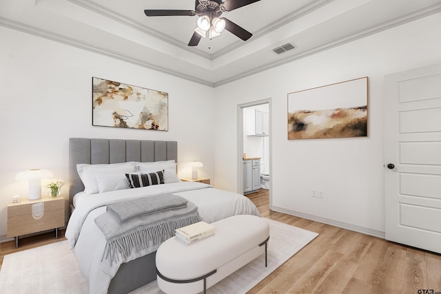 bedroom featuring connected bathroom, ceiling fan, a tray ceiling, crown molding, and light hardwood / wood-style flooring