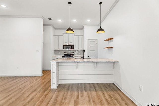 kitchen featuring a kitchen bar, ornamental molding, appliances with stainless steel finishes, kitchen peninsula, and pendant lighting