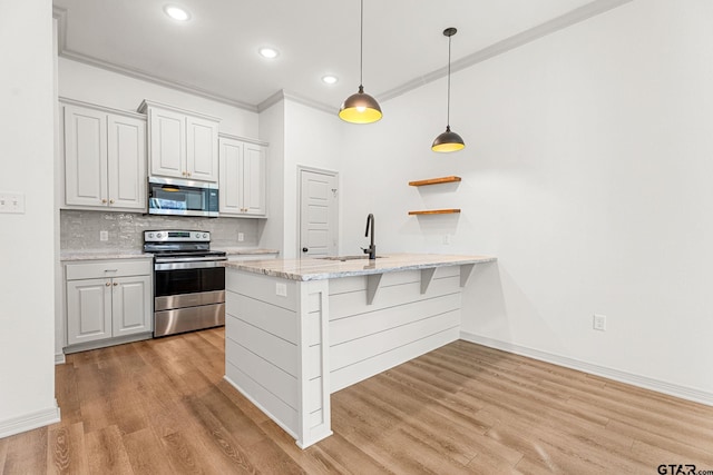 kitchen with sink, hanging light fixtures, stainless steel appliances, light stone counters, and white cabinets