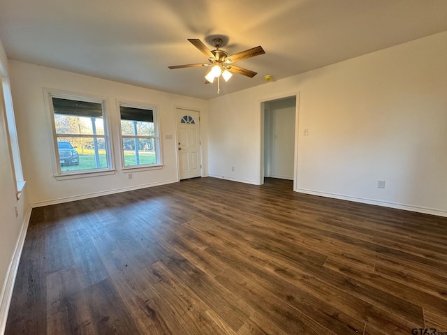 spare room featuring dark wood-style floors, a ceiling fan, and baseboards