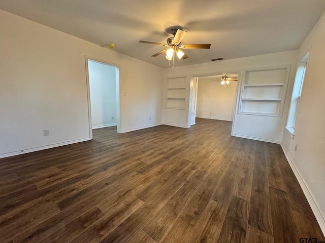 unfurnished room featuring dark wood-style floors, built in shelves, visible vents, and baseboards