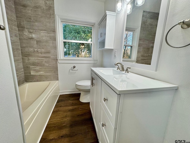 bathroom featuring a healthy amount of sunlight, vanity, toilet, and wood finished floors