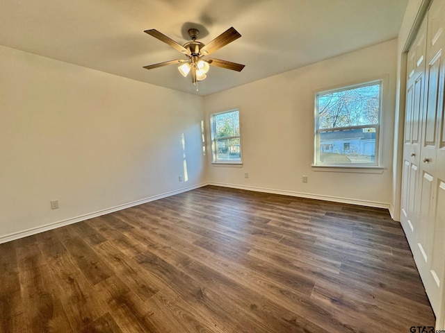 unfurnished room featuring a ceiling fan, dark wood-style flooring, and baseboards