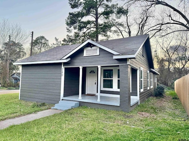 bungalow-style house featuring a front yard, covered porch, and fence