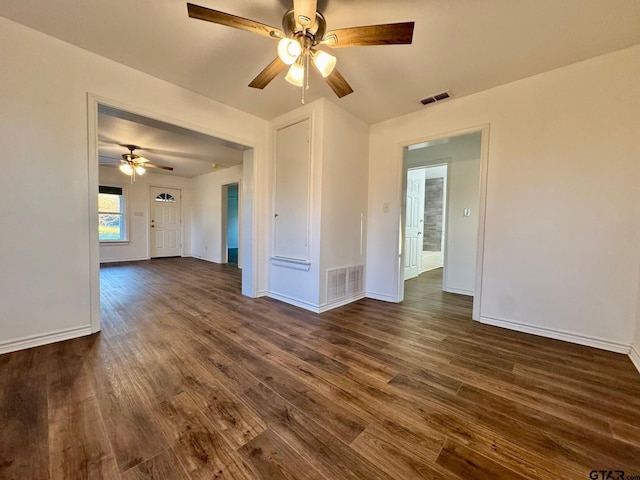 empty room featuring baseboards, visible vents, and dark wood-type flooring