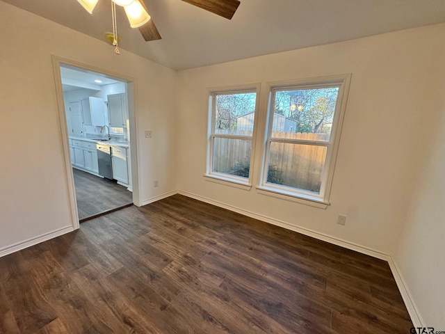 spare room with a sink, dark wood finished floors, baseboards, and ceiling fan