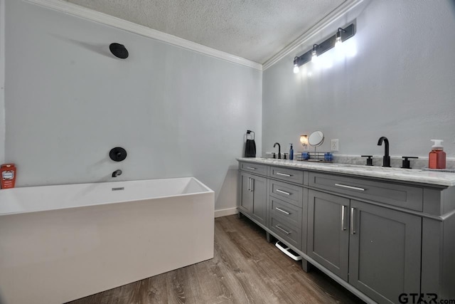 bathroom featuring hardwood / wood-style floors, a textured ceiling, a bathing tub, vanity, and crown molding