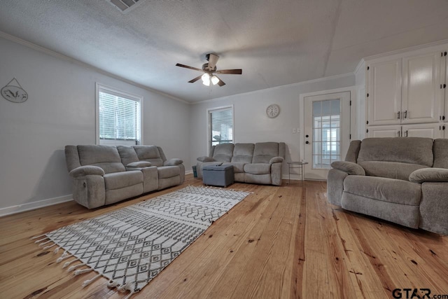 living room featuring a textured ceiling, light wood-type flooring, ceiling fan, and crown molding