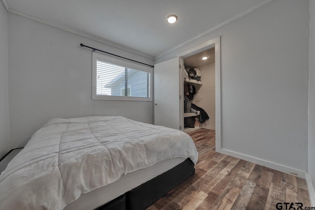 bedroom featuring ornamental molding, a spacious closet, dark wood-type flooring, and a closet