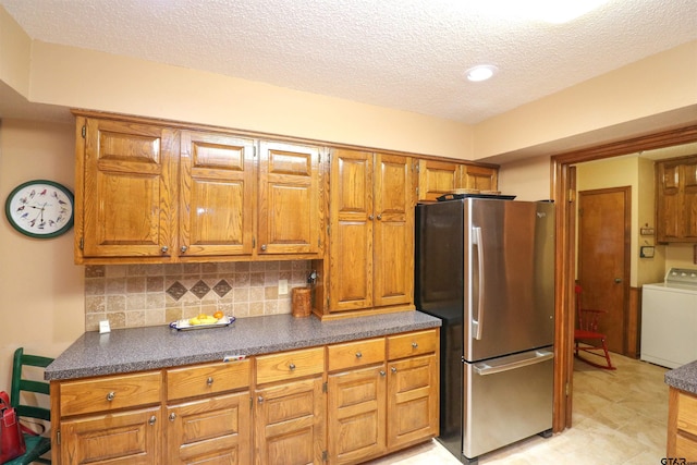 kitchen with tasteful backsplash, stainless steel fridge, washer / dryer, and a textured ceiling