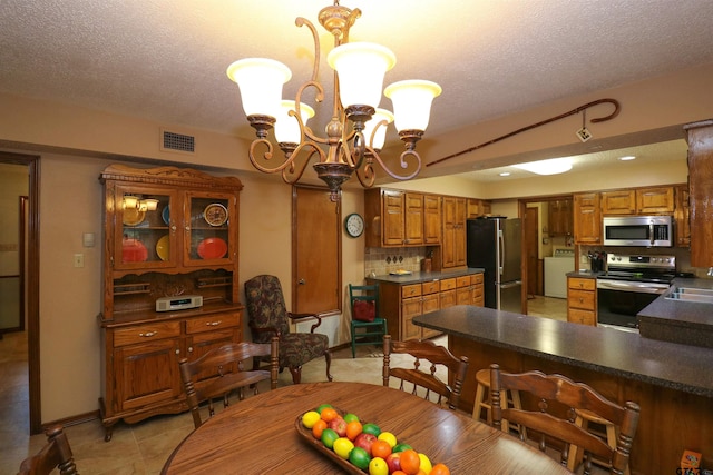 dining room with sink, light tile patterned floors, a textured ceiling, and an inviting chandelier