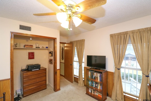 interior space featuring ceiling fan, light carpet, and a textured ceiling