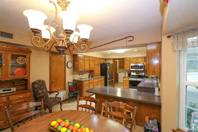 dining area with sink, a textured ceiling, and an inviting chandelier