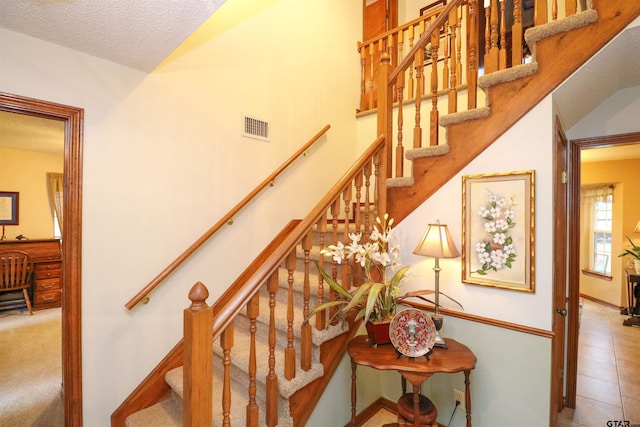 stairway with tile patterned flooring and a textured ceiling