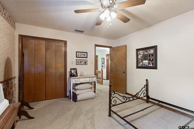 408 E Forest Dr, White Oak, TX 75693 - bedroom featuring light carpet, a closet, a textured ceiling, and a ceiling fan