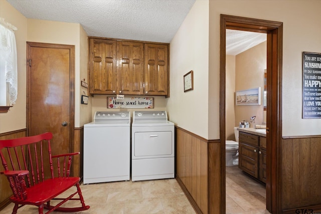 408 E Forest Dr, White Oak, TX 75693 - laundry area with washing machine and dryer, cabinet space, a wainscoted wall, a textured ceiling, and wood walls