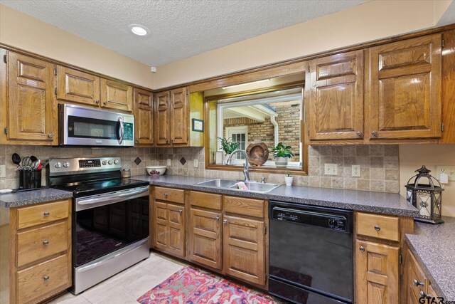 408 E Forest Dr, White Oak, TX 75693 - kitchen featuring appliances with stainless steel finishes, a sink, a textured ceiling, dark countertops, and brown cabinetry