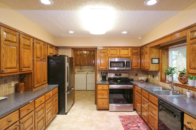 kitchen featuring sink, tasteful backsplash, a textured ceiling, appliances with stainless steel finishes, and independent washer and dryer