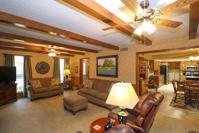 living room featuring plenty of natural light, ceiling fan with notable chandelier, a textured ceiling, and beam ceiling