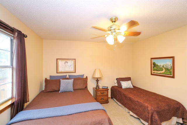 bedroom featuring ceiling fan, light colored carpet, and a textured ceiling