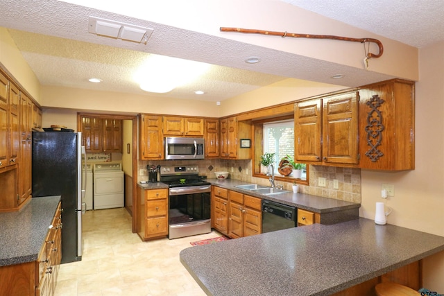 kitchen with tasteful backsplash, sink, stainless steel appliances, washing machine and dryer, and a textured ceiling