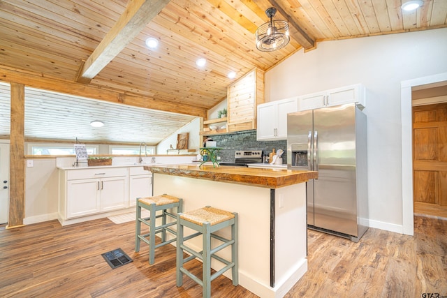 kitchen with appliances with stainless steel finishes, a breakfast bar, white cabinets, a center island, and light wood-type flooring