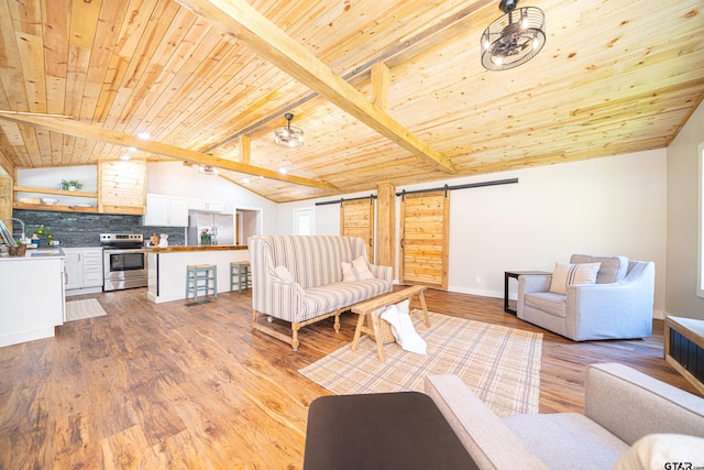 living room with lofted ceiling with beams, a barn door, wooden ceiling, and light wood-type flooring