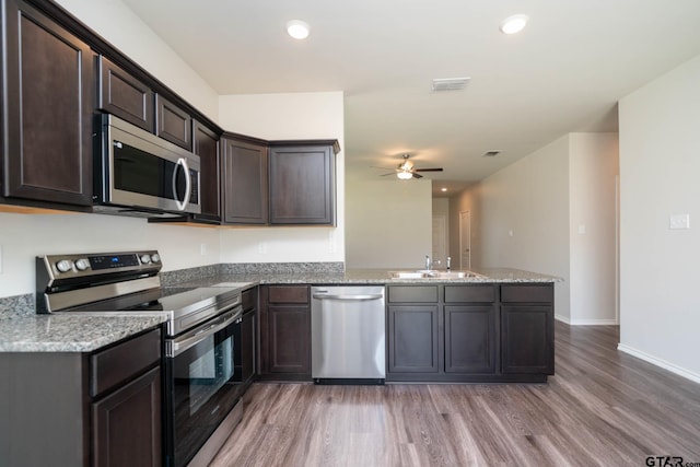 1439 Monterey Dr, Longview, TX 75601 - kitchen featuring appliances with stainless steel finishes, a peninsula, light wood-type flooring, a ceiling fan, and dark brown cabinets