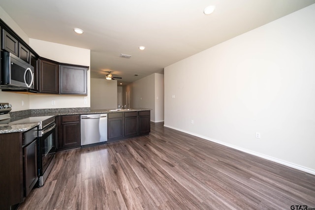 1439 Monterey Dr, Longview, TX 75601 - kitchen with stainless steel appliances, dark wood-style floors, a peninsula, dark brown cabinets, and a ceiling fan