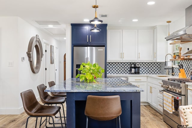 kitchen with light wood-type flooring, decorative light fixtures, a center island, and stainless steel appliances