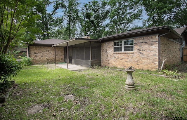 back of property with a lawn, fence, a sunroom, and brick siding