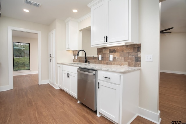 kitchen with stainless steel dishwasher, visible vents, wood finished floors, a sink, and backsplash