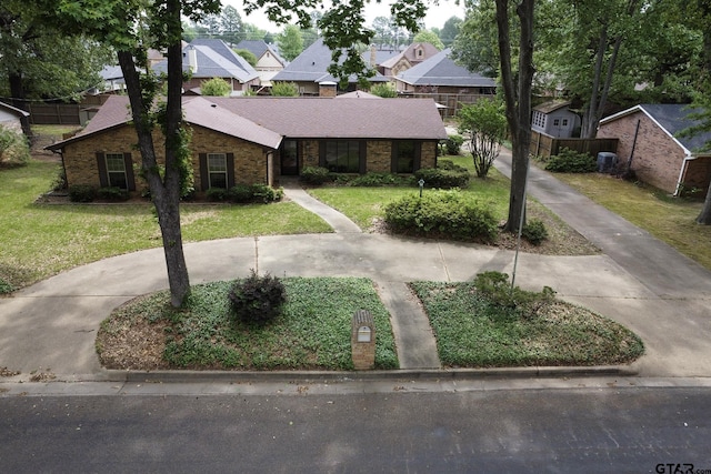 view of front facade featuring brick siding, a shingled roof, a residential view, and a front yard